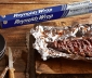 BBQ Ribs in Aluminum Foil Sitting on a Wood Cutting Board