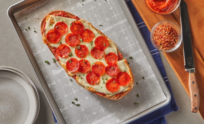 Pepperoni pizza lying on top of a parchment lined baking sheet