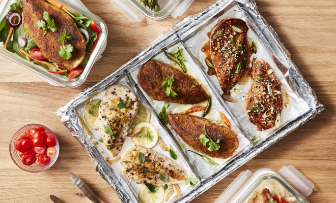 A table with chicken, meat, and other foods on a tray with aluminum foil