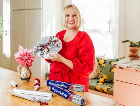 Designer Brittany Jepsen holding a plate wrapped with Reynolds Wrap Fun Foil and tied with a bow