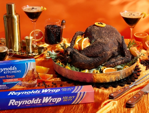 Turkey with an espresso rub sitting on a table alongside a martini and boxes of Reynolds Wrap heavy duty foil and Reynolds Kitchens oven bags