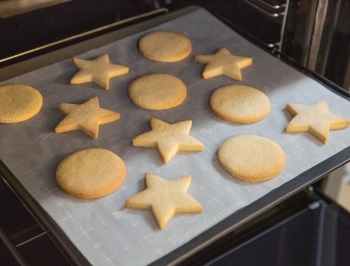 sugar cookies on a parchment lined baking sheet in the oven